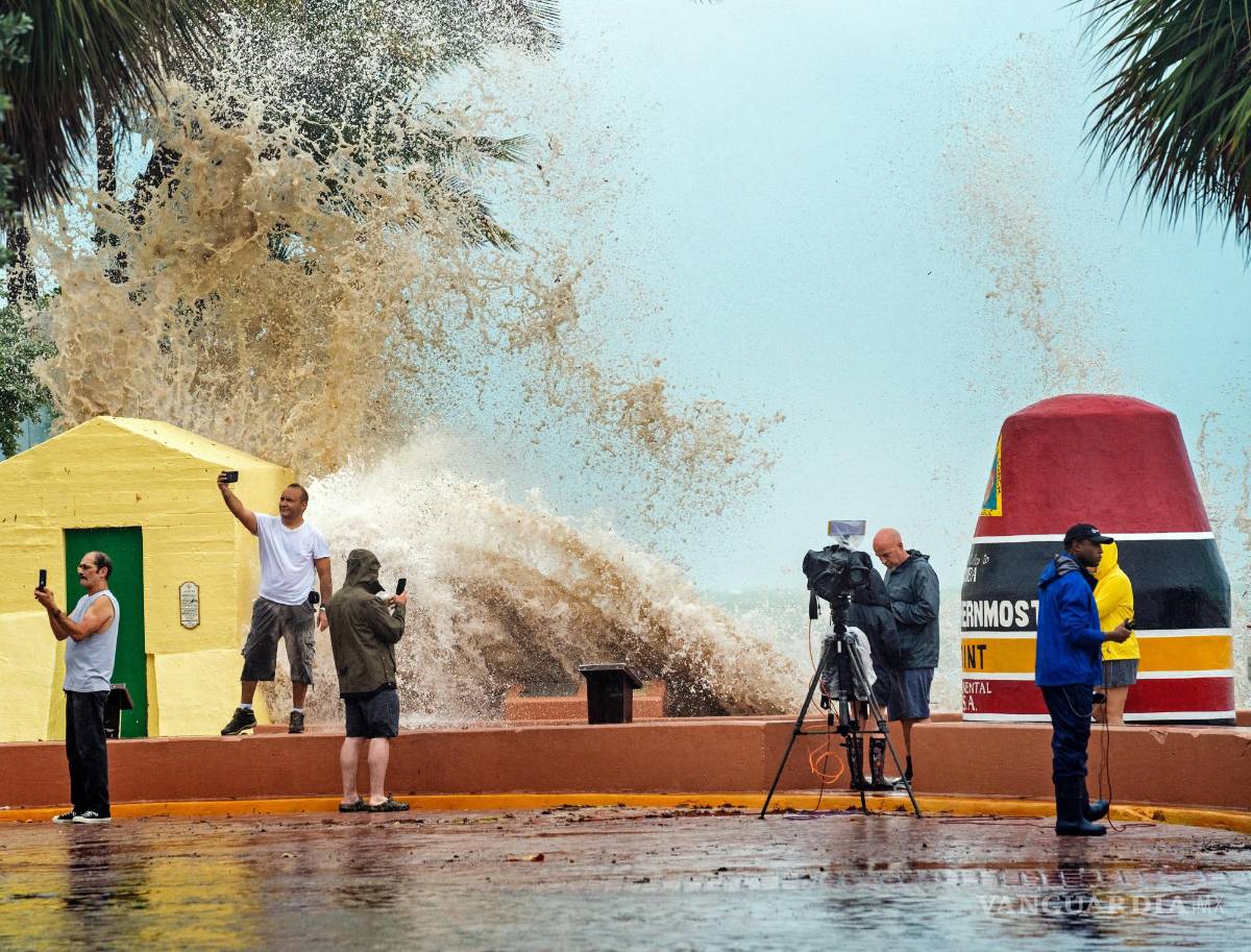 $!Equipos de noticias, turistas y residentes toman imágenes cuando las altas olas del huracán Ian chocan contra el malecón en la boya de Southernmost Point, Florida.