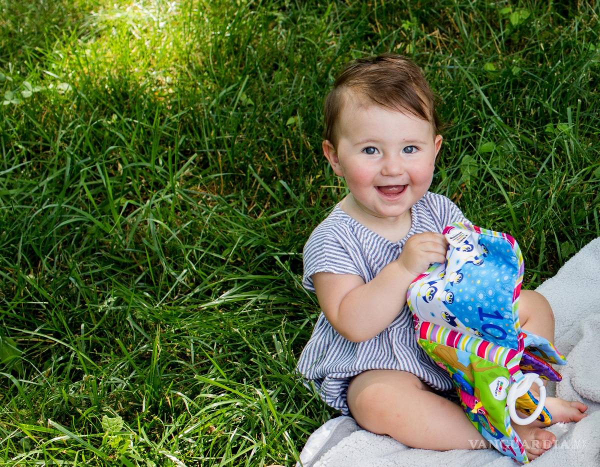 $!Una niña feliz, sin dolor dental, jugando sobre la hierba.