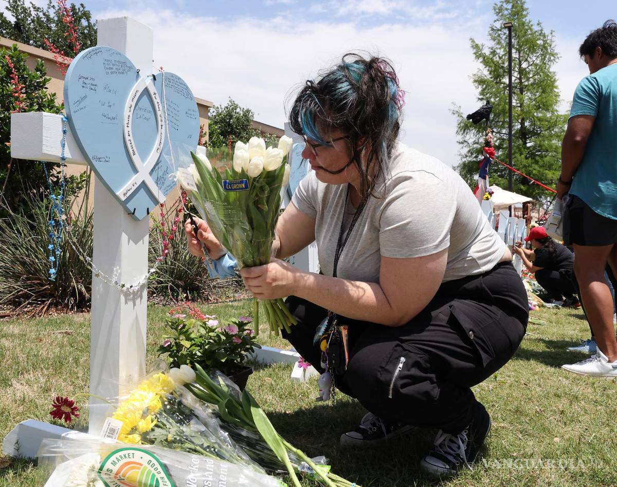 $!Una señora escribe un mensaje a los que murieron y resultaron heridos en una vigilia frente en un tiroteo en Allen Premium Outlets en Allen, Texas.
