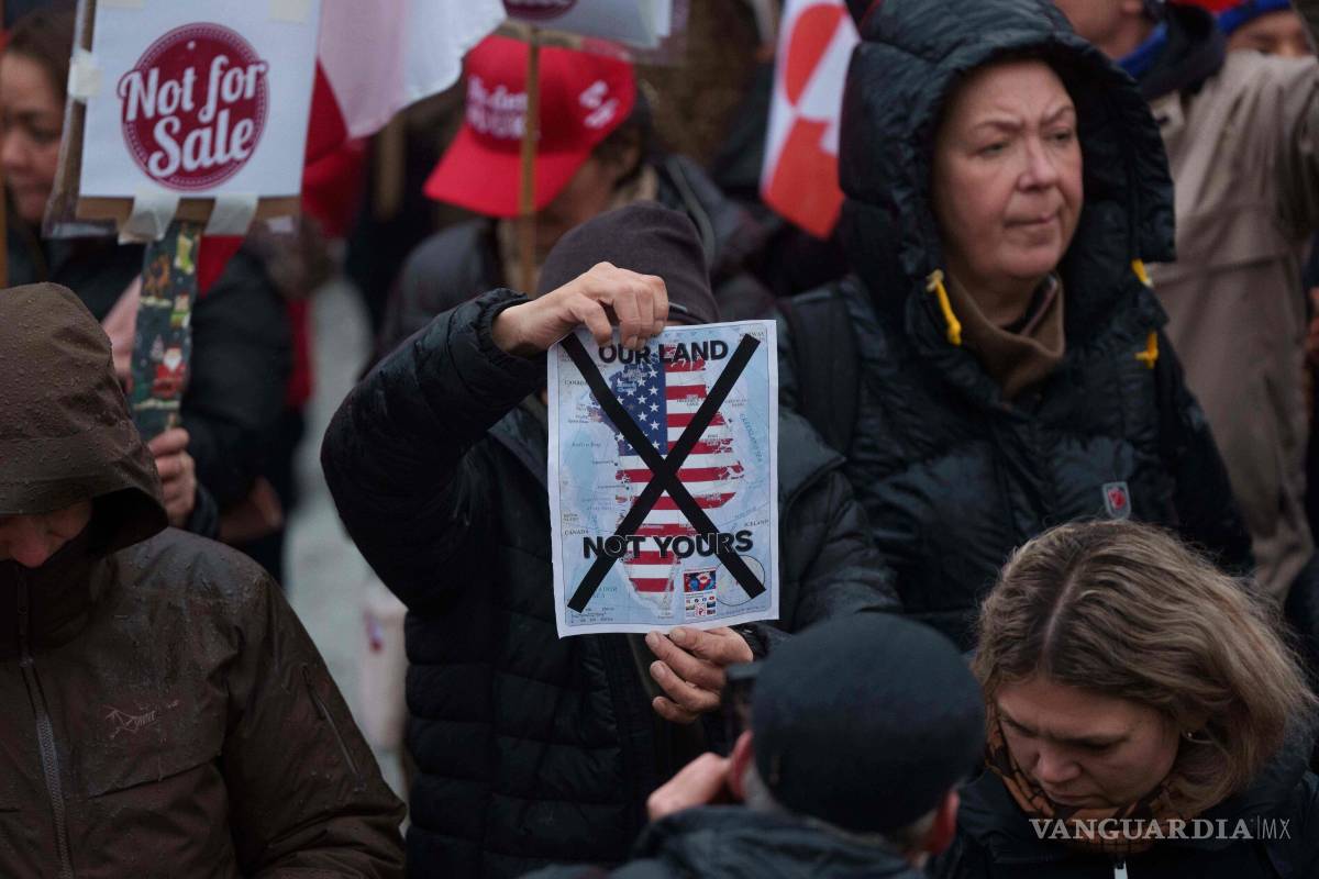 $!Un hombre sostiene un mapa de Groenlandia cubierto con la bandera de EU tachada con una X en una protesta contra la política de Trump en Nuuk.