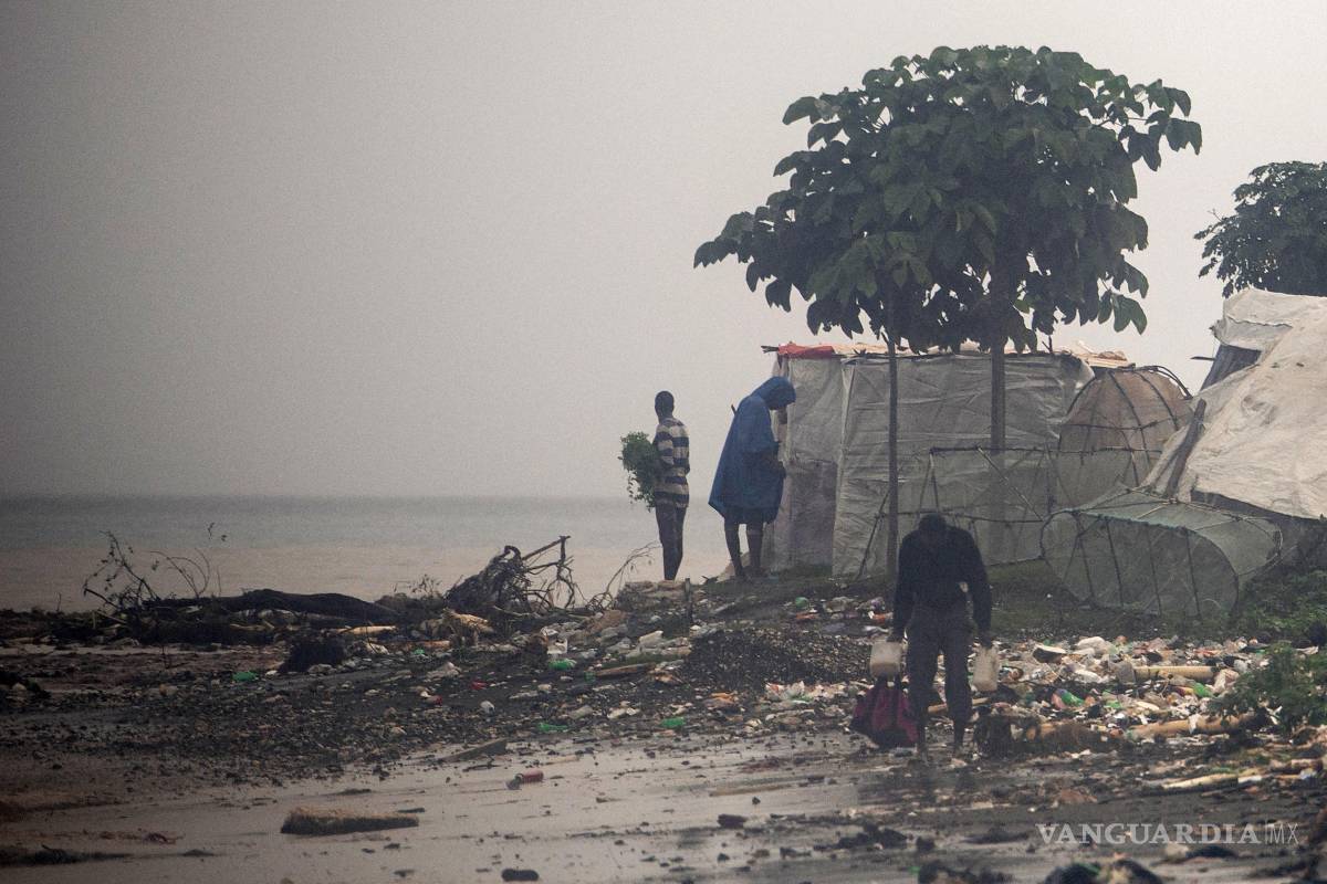 $!Personas caminan por una playa tras el paso del huracán Melissa este jueves, en Petit-Goâve, Haití. Al menos 20 personas murieron y otras diez desaparecieron.