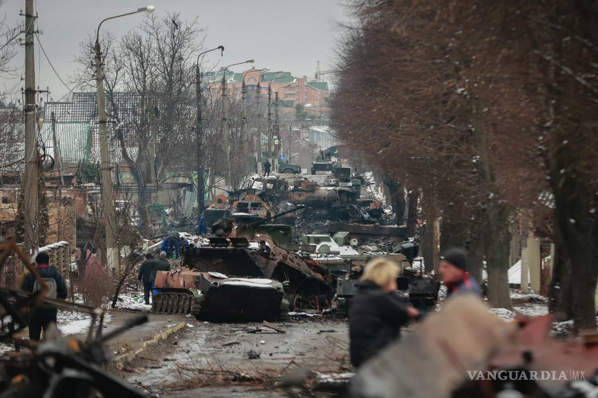 $!Varias personas observan los restos de vehículos militares rusos en una calle de la ciudad de Bucha, cerca de la capital de Ucrania, Kiev, el 1 de marzo de 2022.