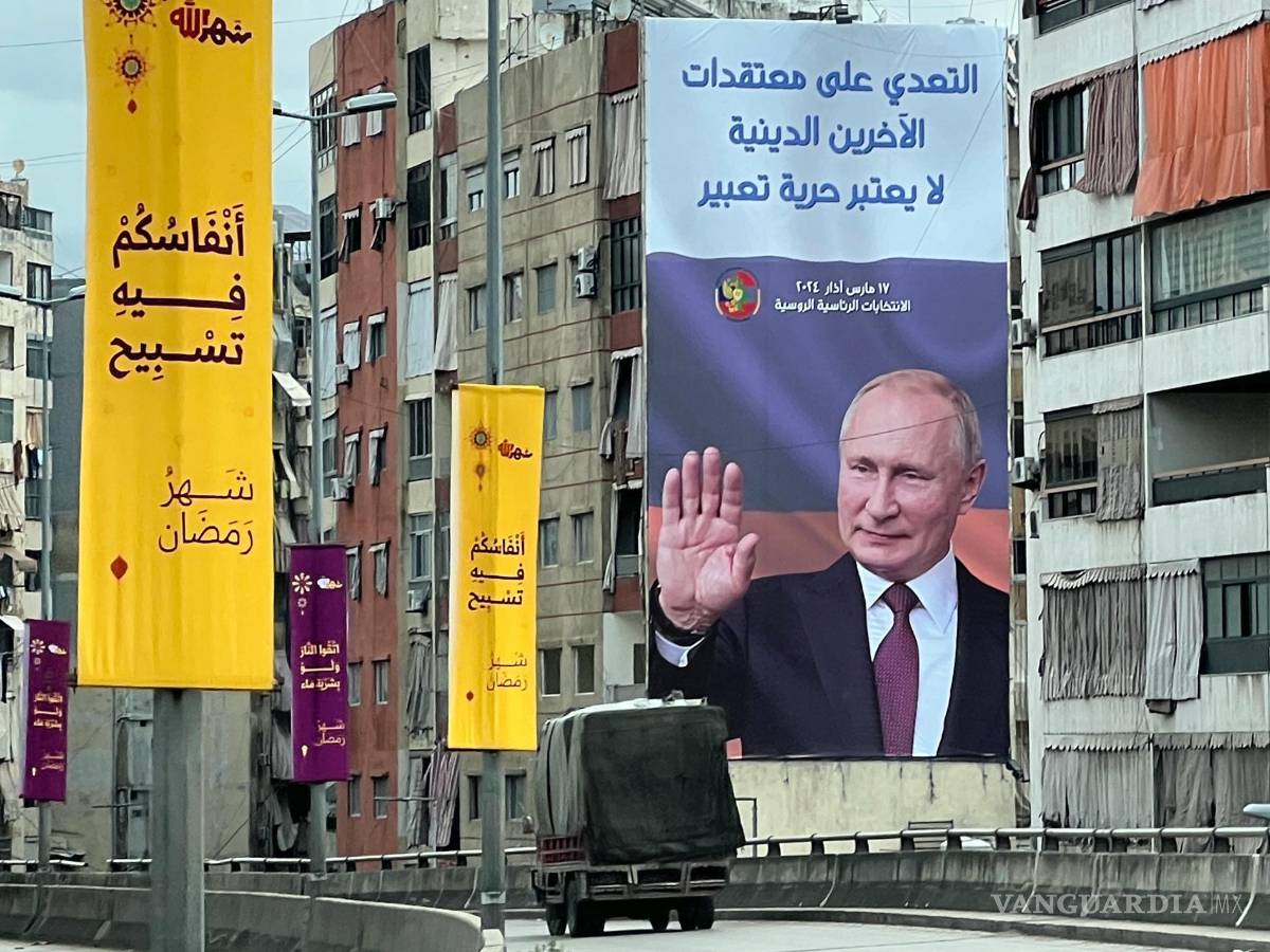 $!Una camioneta frente a un cartel publicitario de las próximas elecciones presidenciales rusas con una imagen de Vladimir Putin, en Beirut, Líbano.