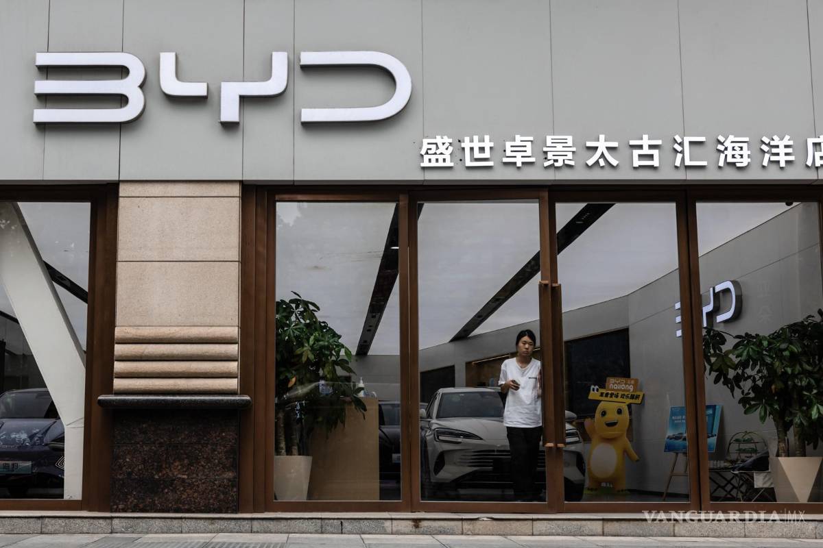 $!Una mujer sale de una tienda del fabricante de vehículos eléctricos BYD, en Shanghai, China.