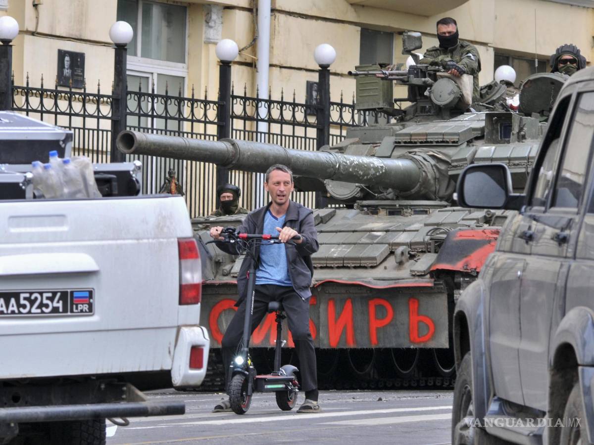 $!Un hombre monta un scooter junto a los militares de la compañía militar privada (PMC) Wagner Group en un tanque que dice ‘Siberia’ en Rostov-on-Don, Rusia.