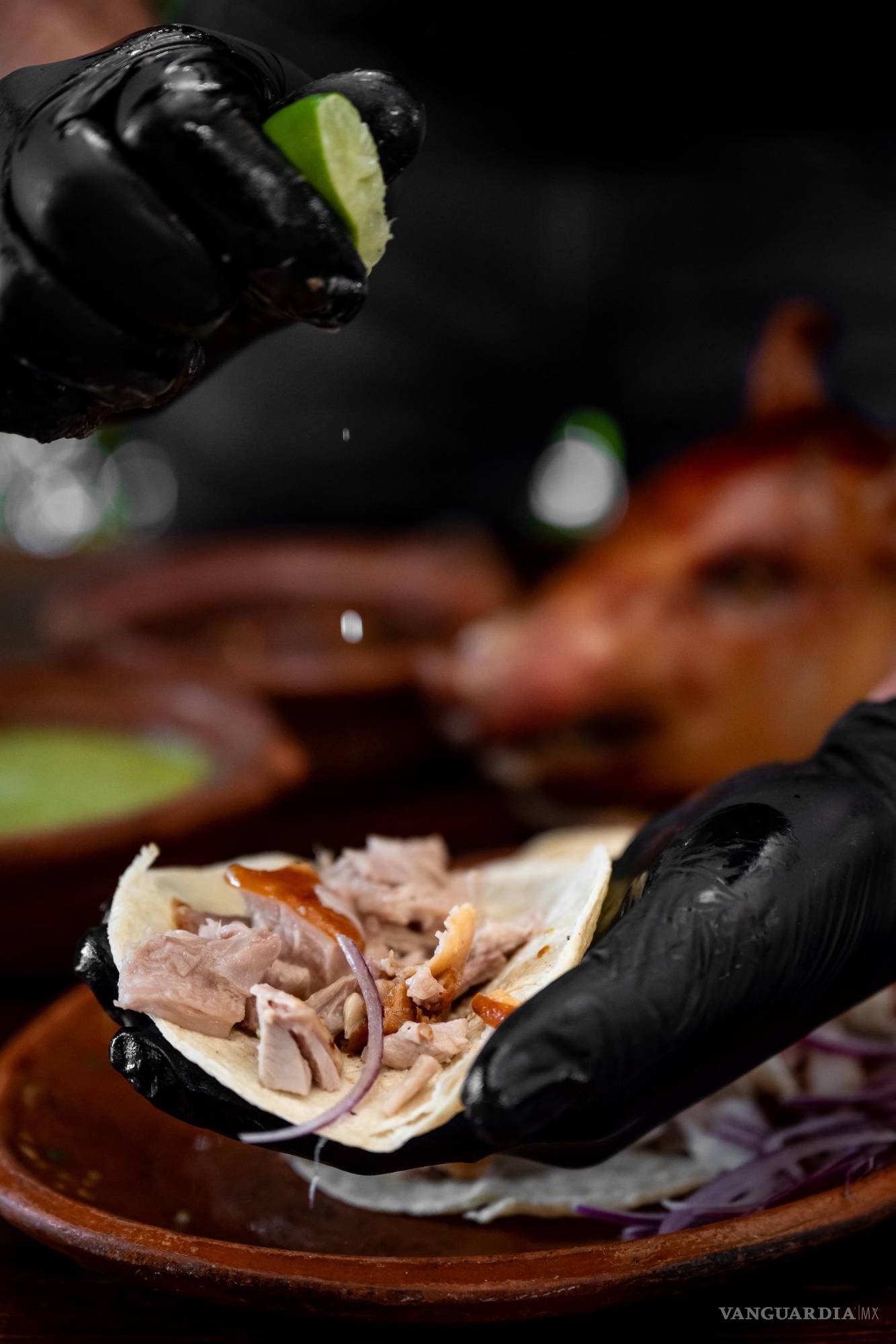 $!Un taco de lechón listo para disfrutarse, con cebolla morada y limón, que realzan su color y sabor.