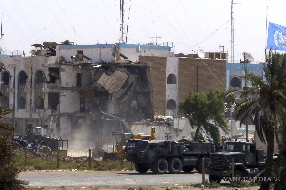 $!Vehículos militares estadounidenses pasan frente a la sección derrumbada de las oficinas de Naciones Unidas, el sábado 23 de agosto de 2003 en Bagdad, Irak.