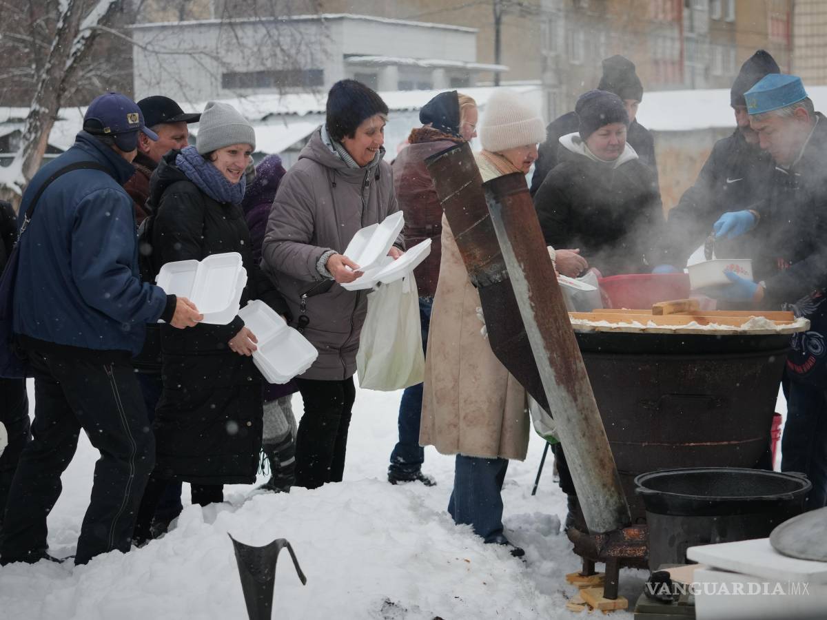 $!El voluntario Marat Darmenov (d) sirve comida caliente gratuita a los residentes de Kiev durante un apagón provocado por los frecuentes ataques aéreos rusos.