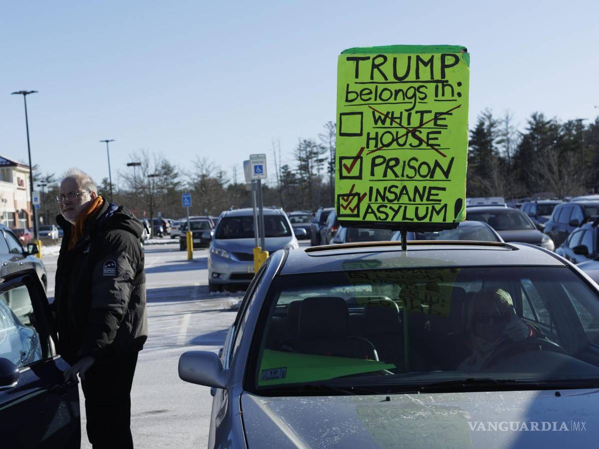 $!Una mujer sostiene un cartel en el techo de su vehículo en protesta contra el expresidente Donald Trump afuera en New Hampshire.
