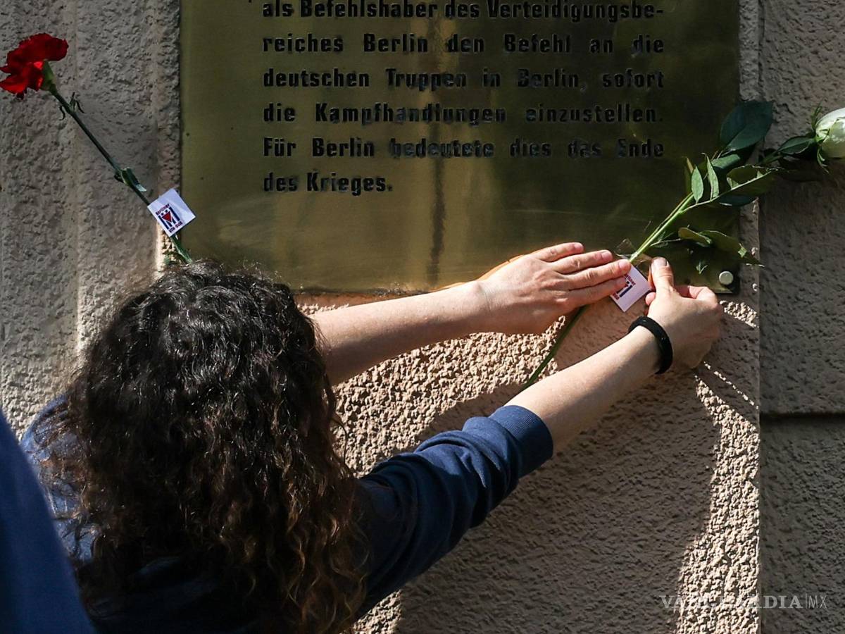 $!Una mujer coloca una flor en la fachada de una casa en el sitio histórico de la Capitulación de Berlín, en la calle Schulenburgring en Berlín, Alemania.