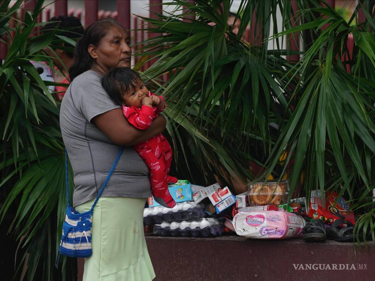 $!Una mujer sostiene a un bebé en brazos junto a varios alimentos tomados de un establecimiento luego del paso del huracán Otis por Acapulco, Guerrero (México).