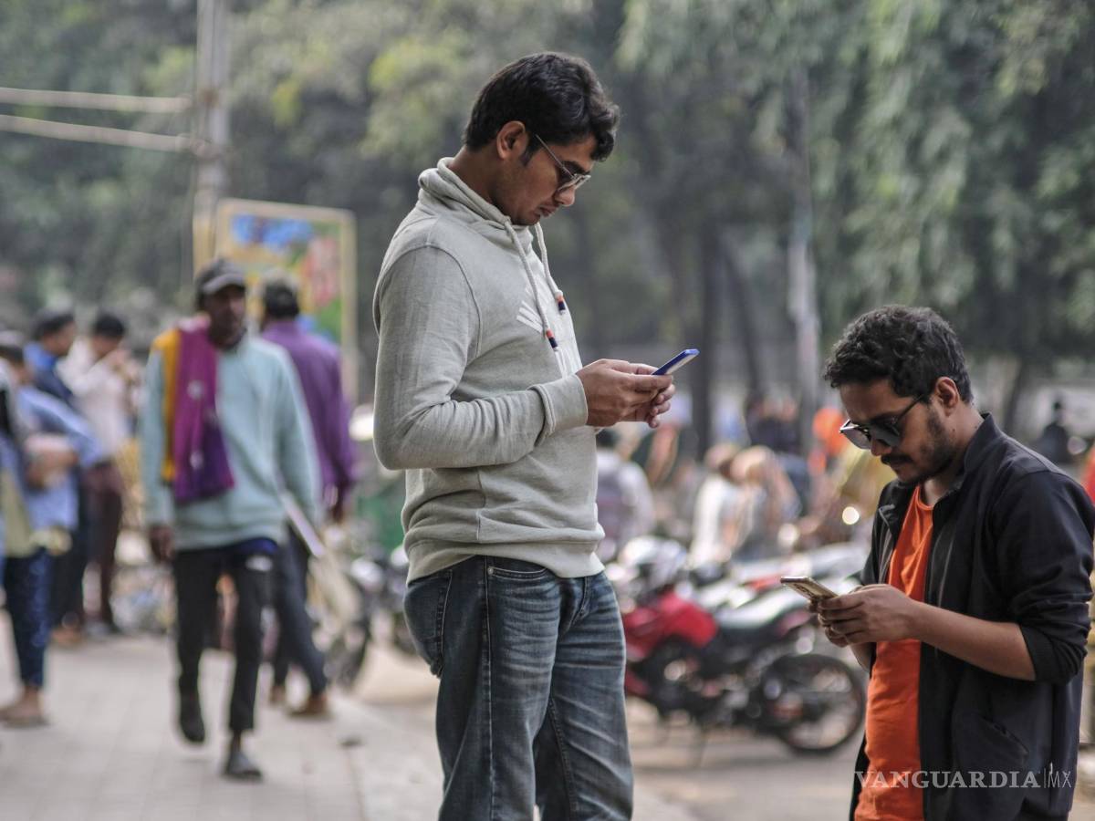 $!Dos personas revisan sus celulares en la Universidad de Dhaka, Bangladesh. Con un deepfake, la imagen de un candidato se puede distorsionar o suavizar.