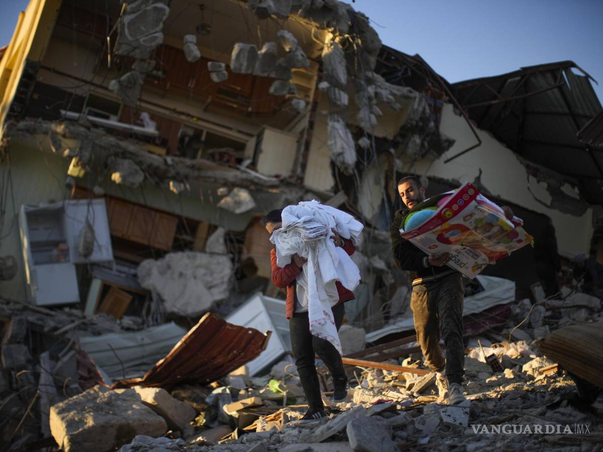 $!Residentes trasladan sus pertenencias desde su vivienda en un edificio destrozado por un potente sismo, en Samandag.