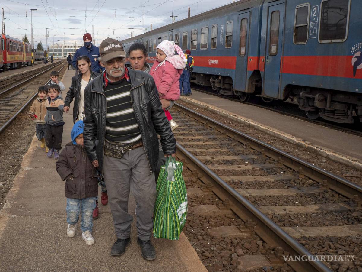 $!Refugiados que huyen de la guerra en la vecina Ucrania caminan sobre un andén en Zahony, Hungría. AP/Balazs Kaufmann
