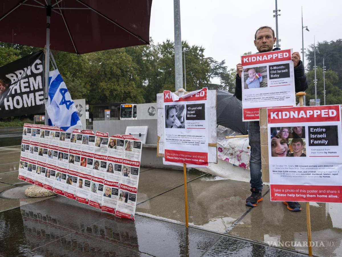 $!Un manifestante sostiene un cartel junto a pancartas con fotografías de rehenes tomados por Hamás junto a la sede europea de las Naciones Unidas en Ginebra.