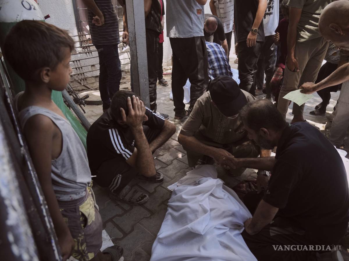 $!Dolientes se reúnen en torno a los cadáveres de los palestinos que murieron al intentar llegar a los camiones de ayuda que ingresan al norte de Gaza.