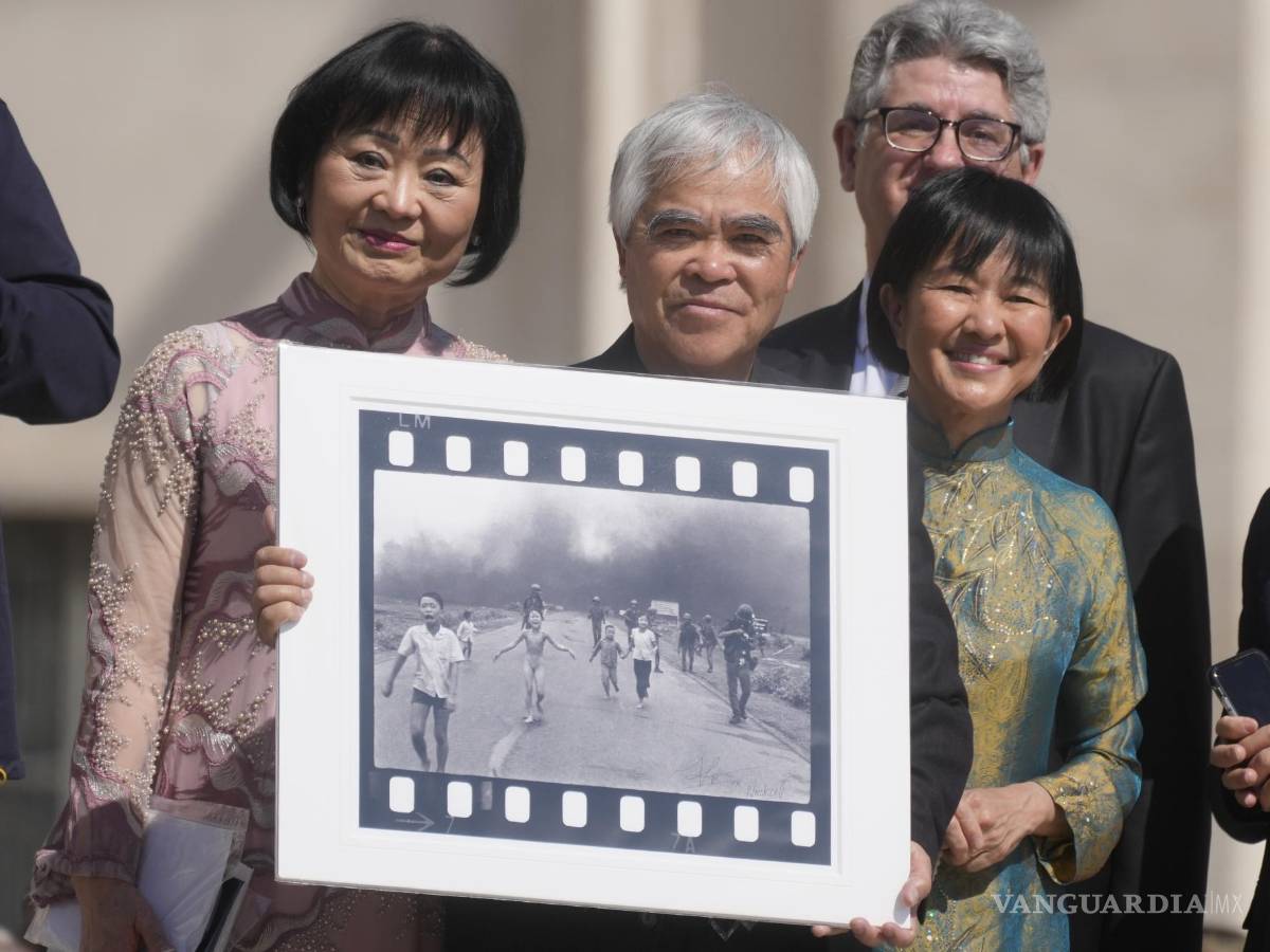 $!El fotógrafo ganador del Premio Pulitzer Nick Ut (c), flanqueado por Kim Phuc (i) sostiene la “Niña del napalm” en la Plaza de San Pedro en el Vaticano.