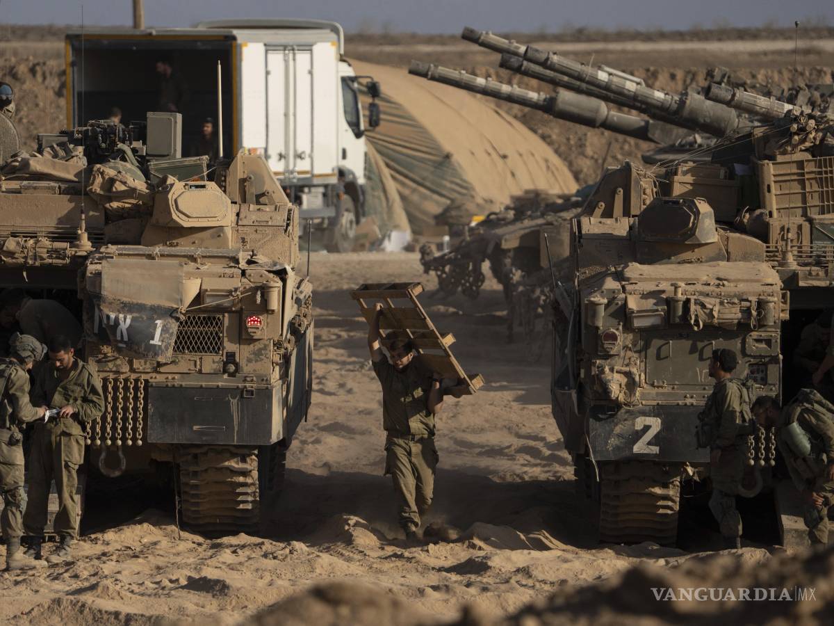 $!Soldados israelíes trabajan en sus vehículos blindados estacionados en una zona de preparación cerca de la frontera entre Israel y Gaza.
