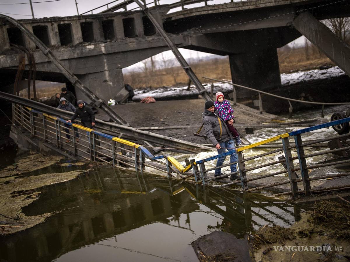 $!La combatiente Valery, de 37 años, carga a un niño mientras ayuda a una familia a cruzar un puente que fue destruido por artillería, el miércoles 2 de marzo de 2022, en Kiev. (AP Foto/Emilio Morenatti)