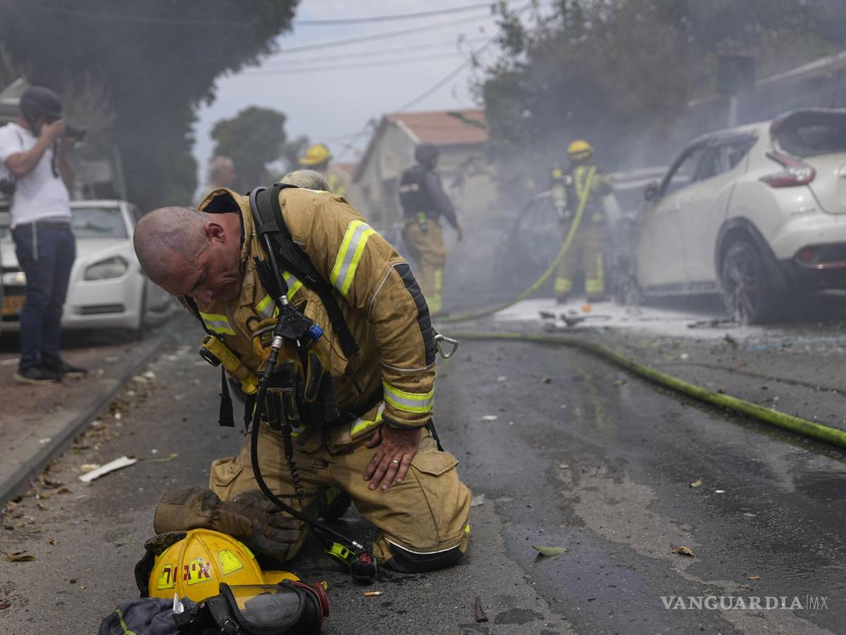 $!Un bombero israelí se arrodilla exhausto después de que él y sus compañeros apagaron vehículos incendiados por los cohetes lanzados desde la Franja de Gaza, el lunes 9 de octubre de 2023, en Ascalón, Israel. (AP Foto/Ohad Zwigenberg)