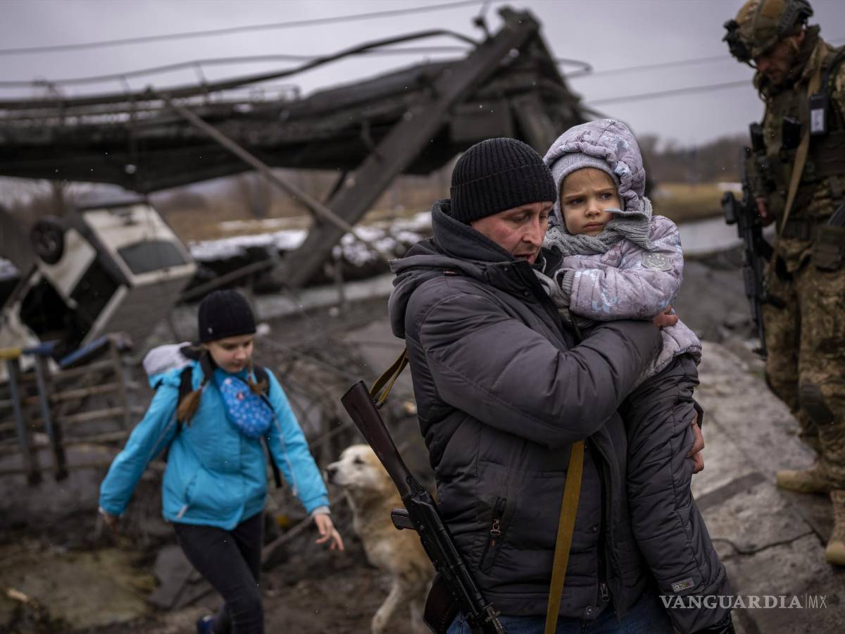 $!El miliciano local Valery, de 37 años, ayuda a una familia que huye junto a un puente destruido por fuego de artillería a las afueras de Kiev. AP/Emilio Morenatti
