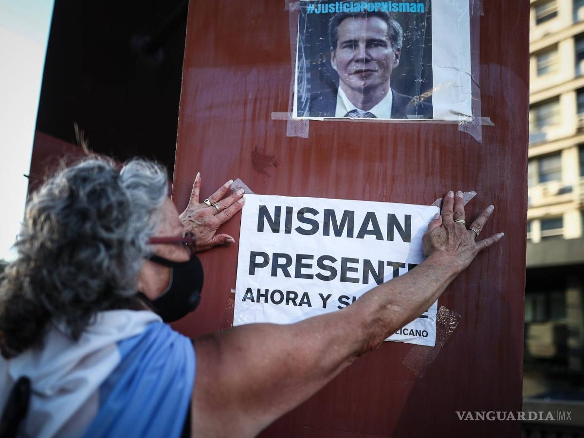 $!Fotografía del 18 de enero de 2021. Una mujer cuelga un cartel en un retrato del fiscal argentino Alberto Nisman, en un acto por el sexto aniversario de su muerte.