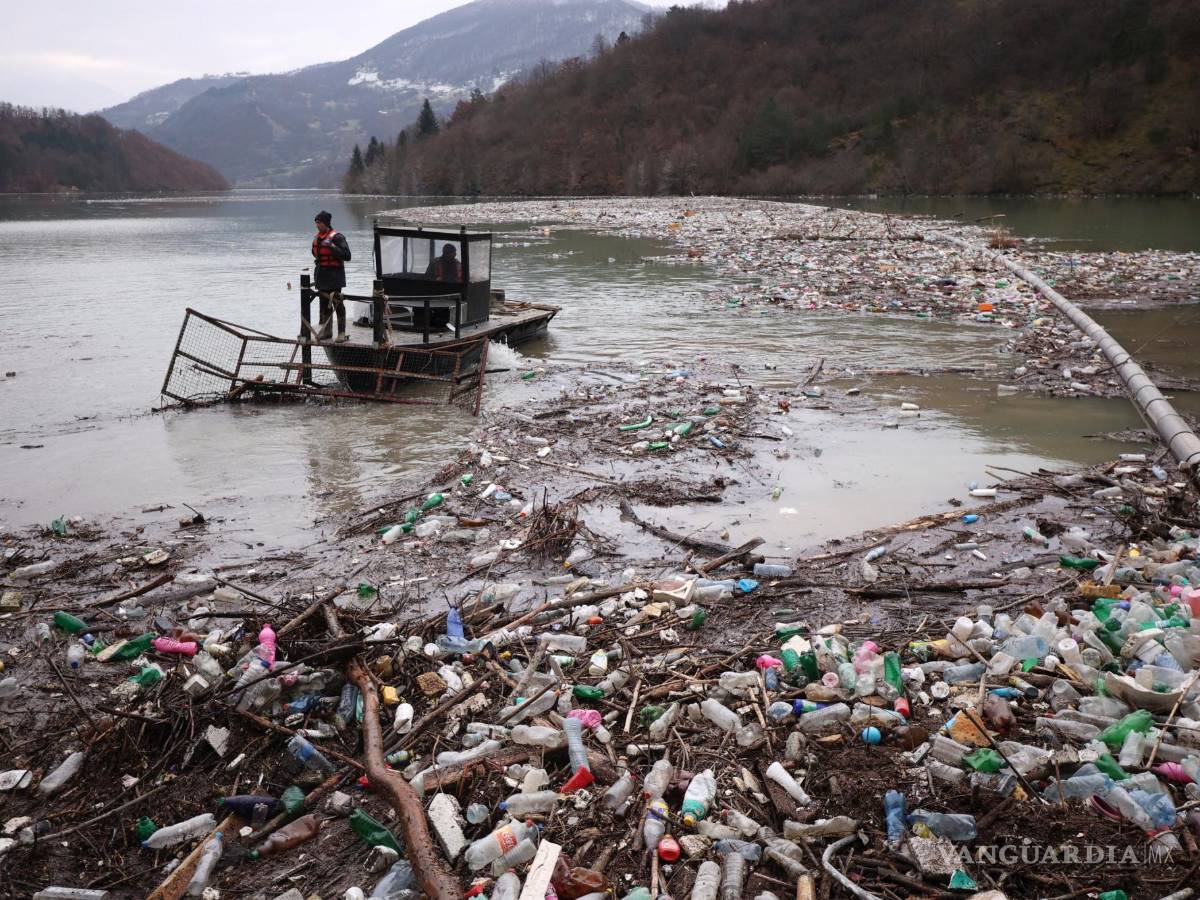 $!Los trabajadores de una empresa de servicios públicos empujan los desechos a la orilla del río Lim, cerca de Priboj, Serbia.