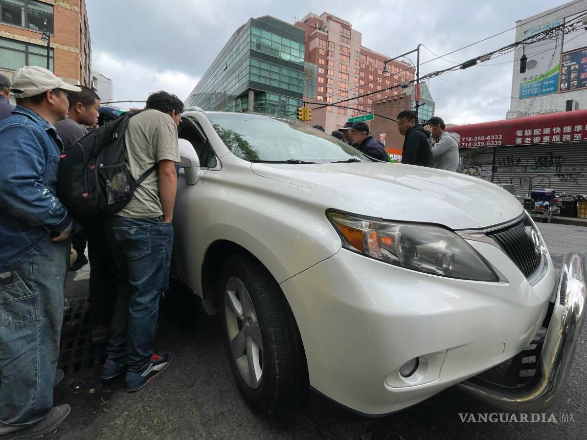 $!Wang Gang, de 36 años, centro izquierda, inmigrante chino, conversa con el conductor de un coche para conseguir un trabajo en el barrio de Flushing.