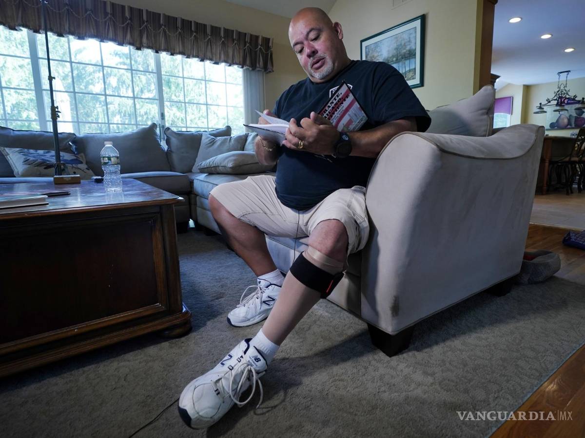 $!Will Jimeno, un ex agente de policía de la Autoridad Portuaria que fue rescatado de entre los escombros del World Trader Center el 11S, lee el libro ilustrado para niños que escribió Immigrant, American, Survivor (“Inmigrante, Estadounidense, Sobreviviente”) contando su experiencia, durante una entrevista en su casa en Chester, Nueva Jersey, el 2 de agosto de 2021. Herido en el 11S, Jimeno usa una media de compresión y un brazalete en su pierna izquierda. AP/Richard Drew