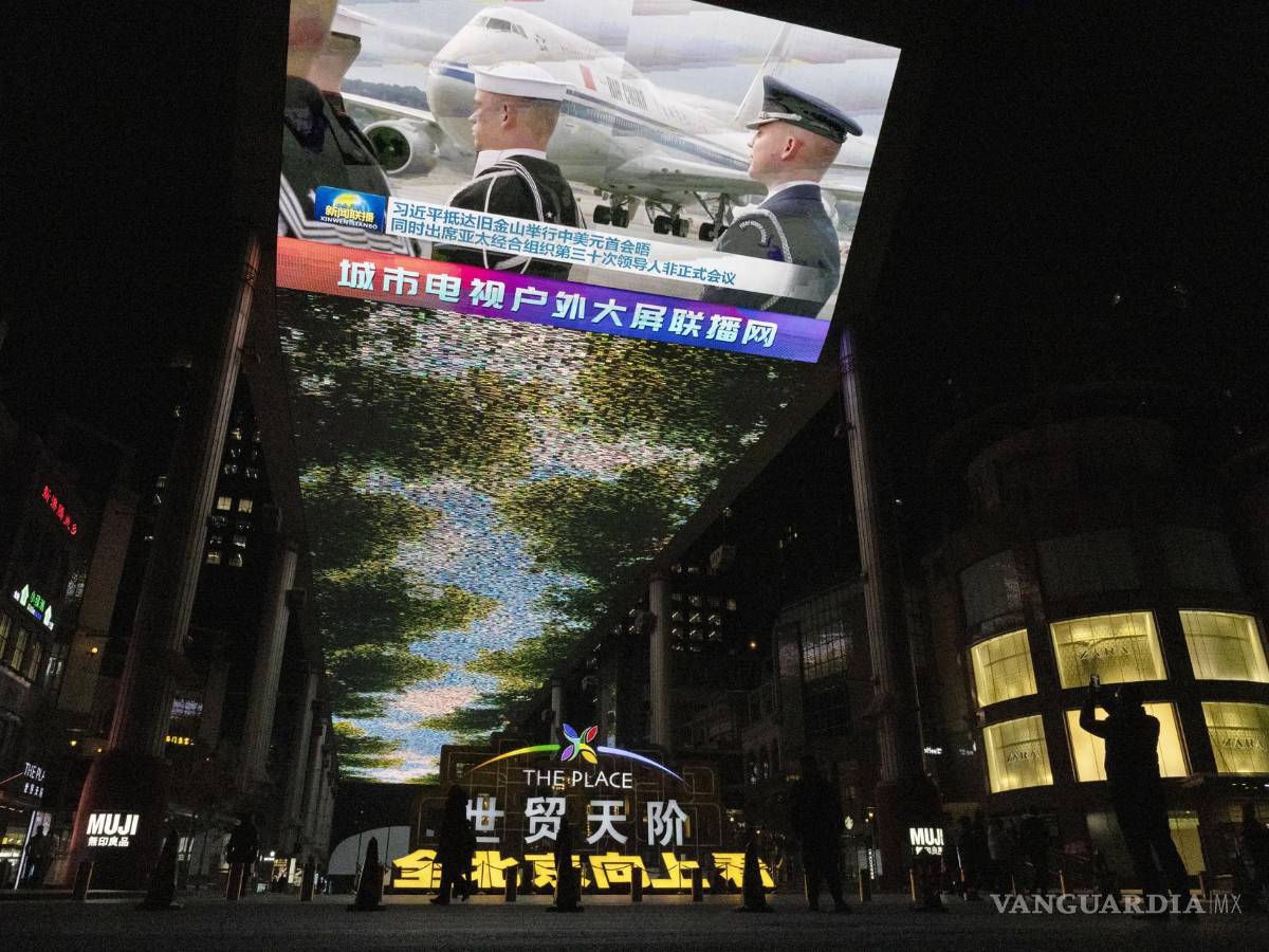 $!Un hombre (d) toma una fotografía de una gran pantalla que muestra la llegada del presidente chino Xi Jinping a Estados Unidos, en un centro comercial de Beijing.