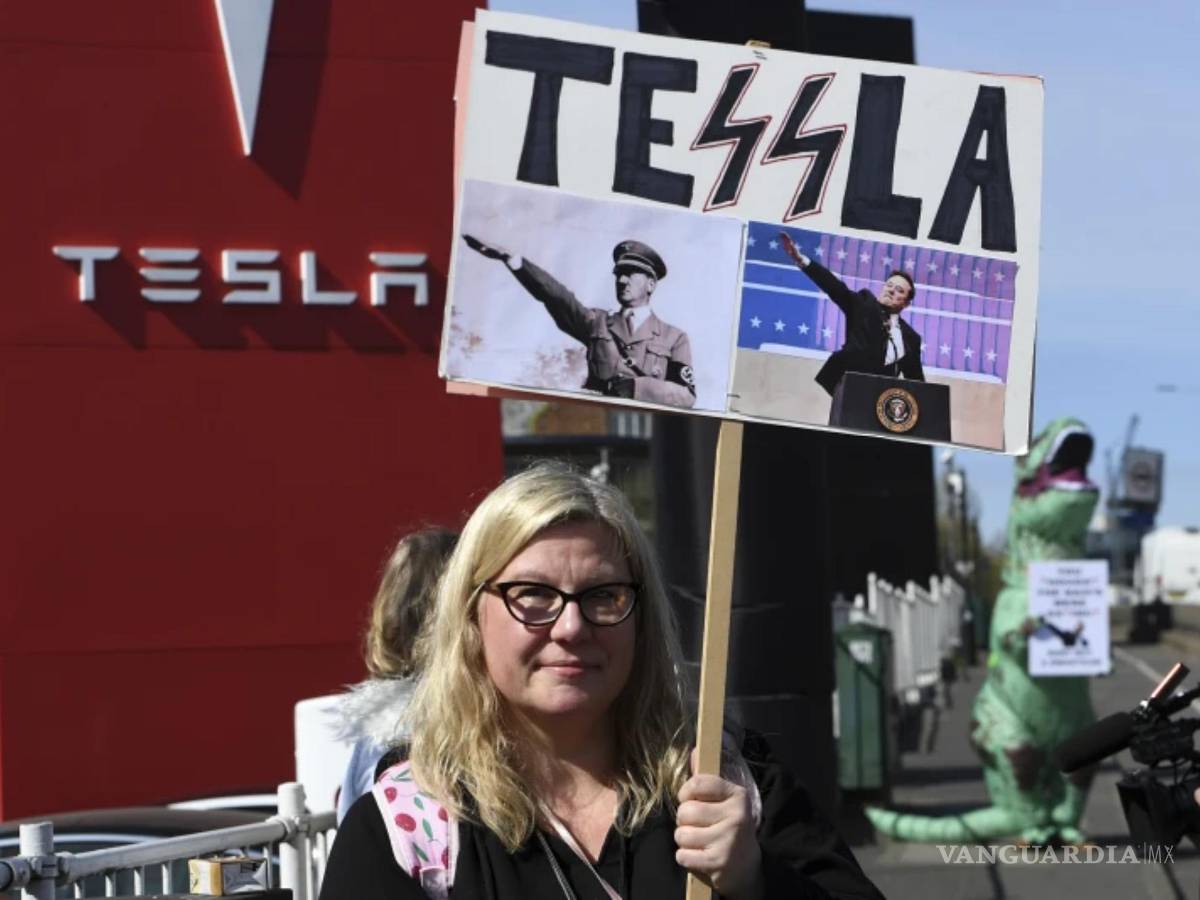 $!Una manifestante sostiene una pancarta mientras participa en el Día de Acción Global para Derribar Tesla cerca de un concesionario de Tesla en Londres.
