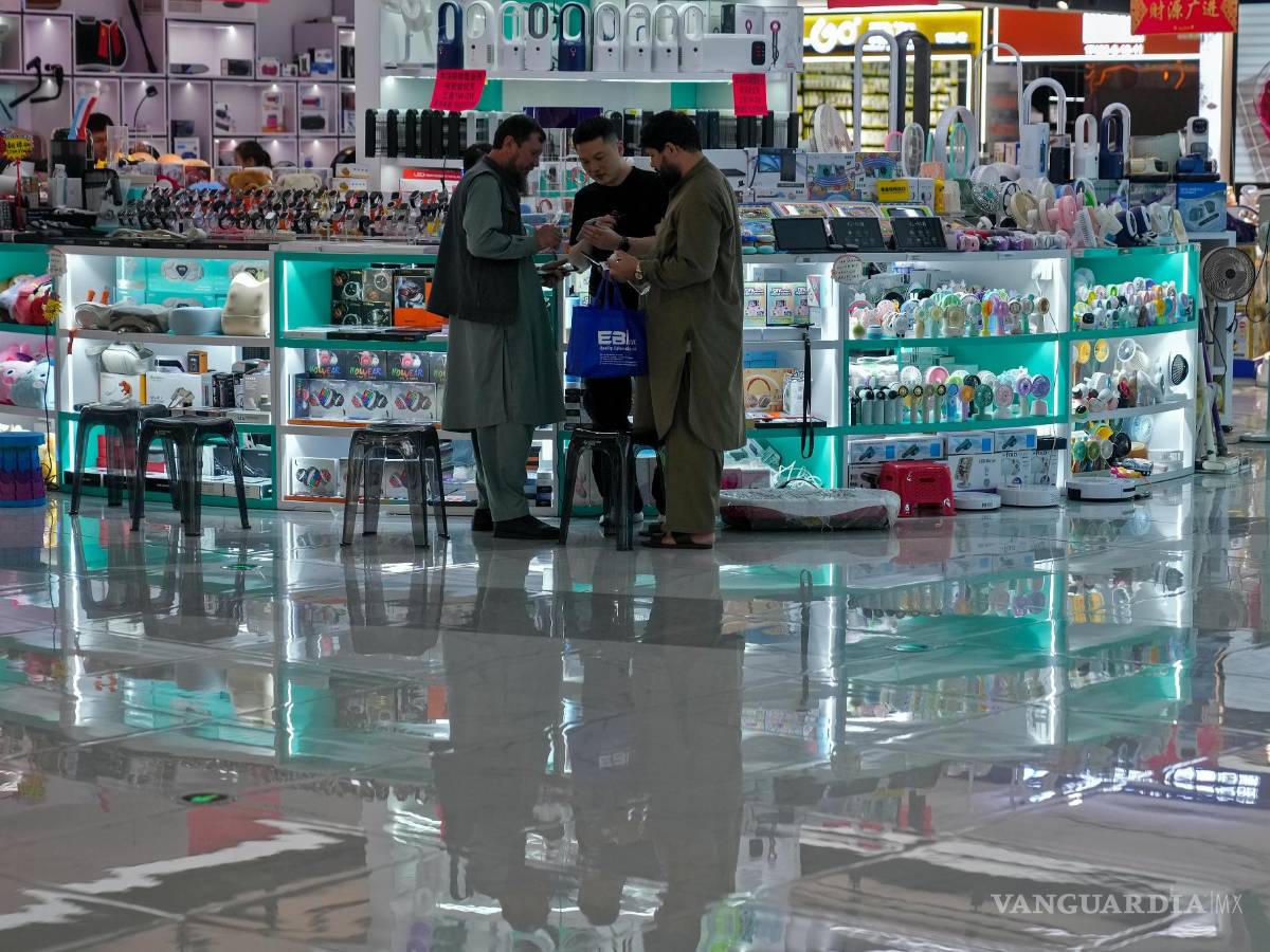 $!Compradores extranjeros consultan precios con un vendedor en una tienda que vende productos electrónicos en el mercado de Yiwu, en Yiwu en China.