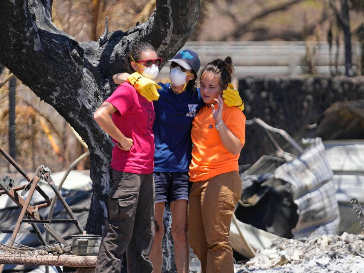 $!Las mujeres se abrazan después de excavar entre los escombros de una casa destruida por un incendio forestal en Lahaina, Hawái.