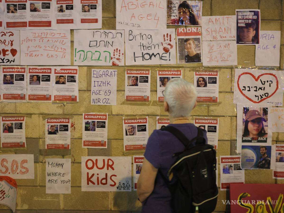 $!Una persona mira fotografías de rehenes retenidos por militantes de Hamas durante una protesta pidiendo al gobierno israelí que ayude a rescatarlos.