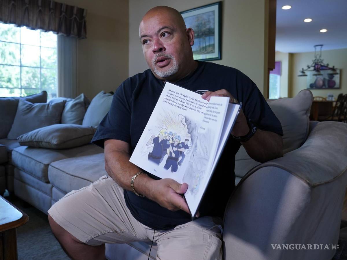 $!Will Jimeno, un ex agente de policía de la Autoridad Portuaria que, tras muchas horas, fue rescatado de entre los escombros del World Trader Center el 11S, sostiene el libro ilustrado para niños que escribió Immigrant, American, Survivor (“Inmigrante, Estadounidense, Sobreviviente”), en el que cuenta su experiencia, durante una entrevista en su casa es Chester, Nueva Jersey, el 2 de agosto de 2021. AP/Richard Drew