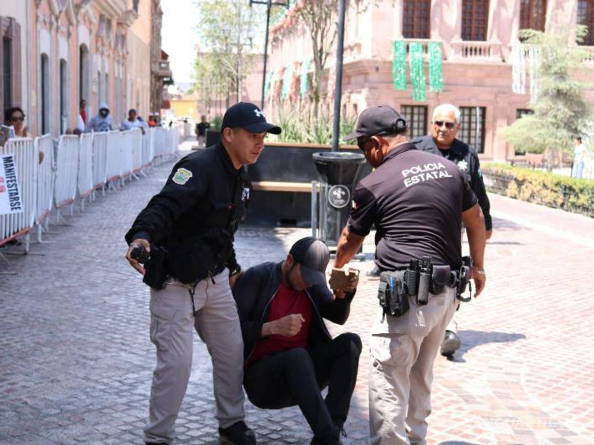 $!Policías del Palacio de Gobierno detienen con violencia al joven activista Jonathan Palacios después de que cruzara las vallas que cercaban la plaza.