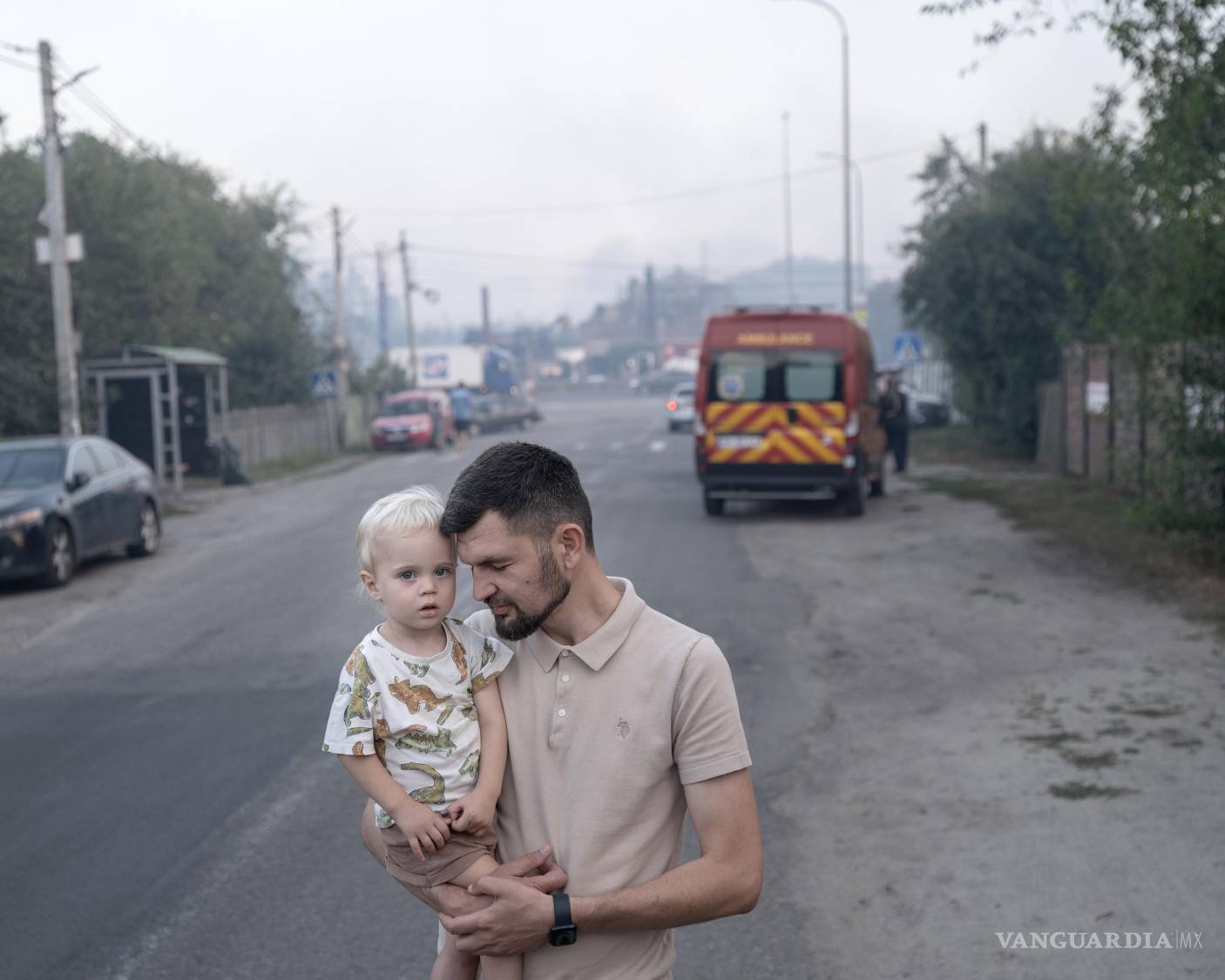 $!Oleh Biliuk y su hijo de dos años, Yarema, observan el humo que se eleva desde un depósito de municiones en llamas cerca de su casa en Myla, en la región de Kiev.
