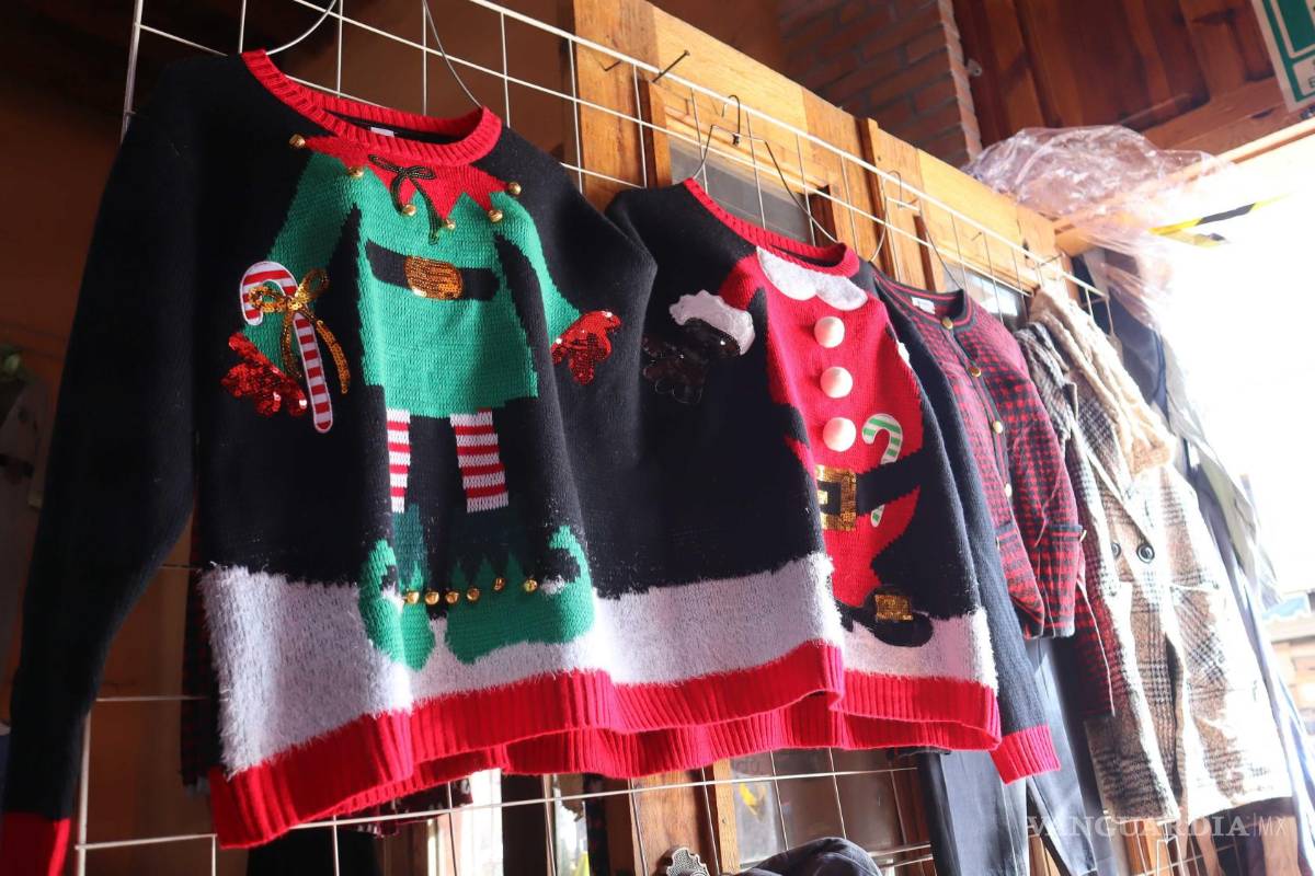 $!Coloridos suéteres con motivos navideños cuelgan en un tendedero, listos para ser adquiridos durante la temporada festiva en la ciudad.