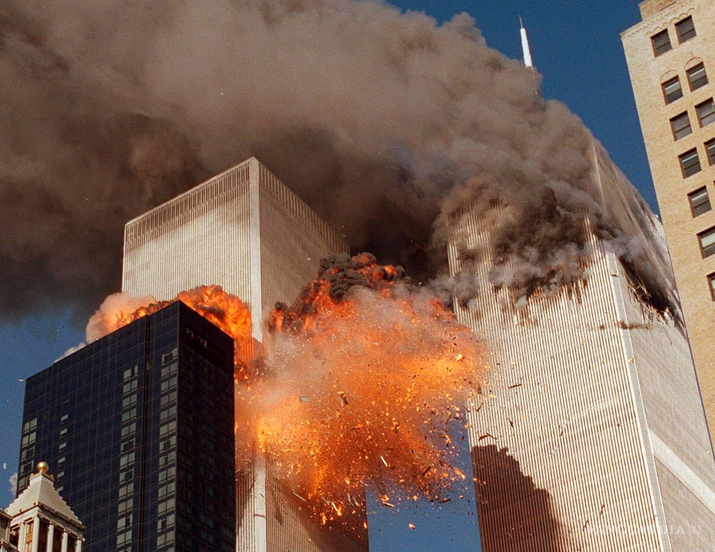 $!Una columna de humo se eleva desde una de las torres del WTC, mientras llamas y escombros estallan en la segunda torre, el 11 de septiembre de 2001, en Nueva York.