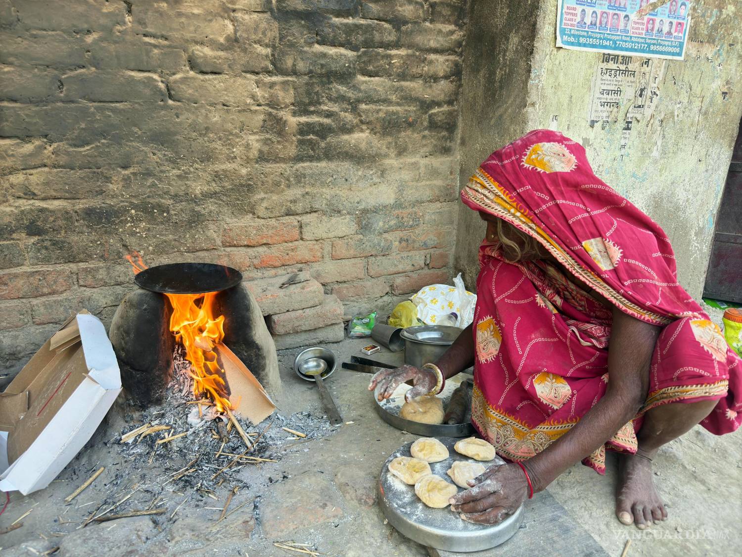 $!Una mujer cocina con leña frente a su casa en Prayagraj, India, el viernes 24 de abril de 2026.