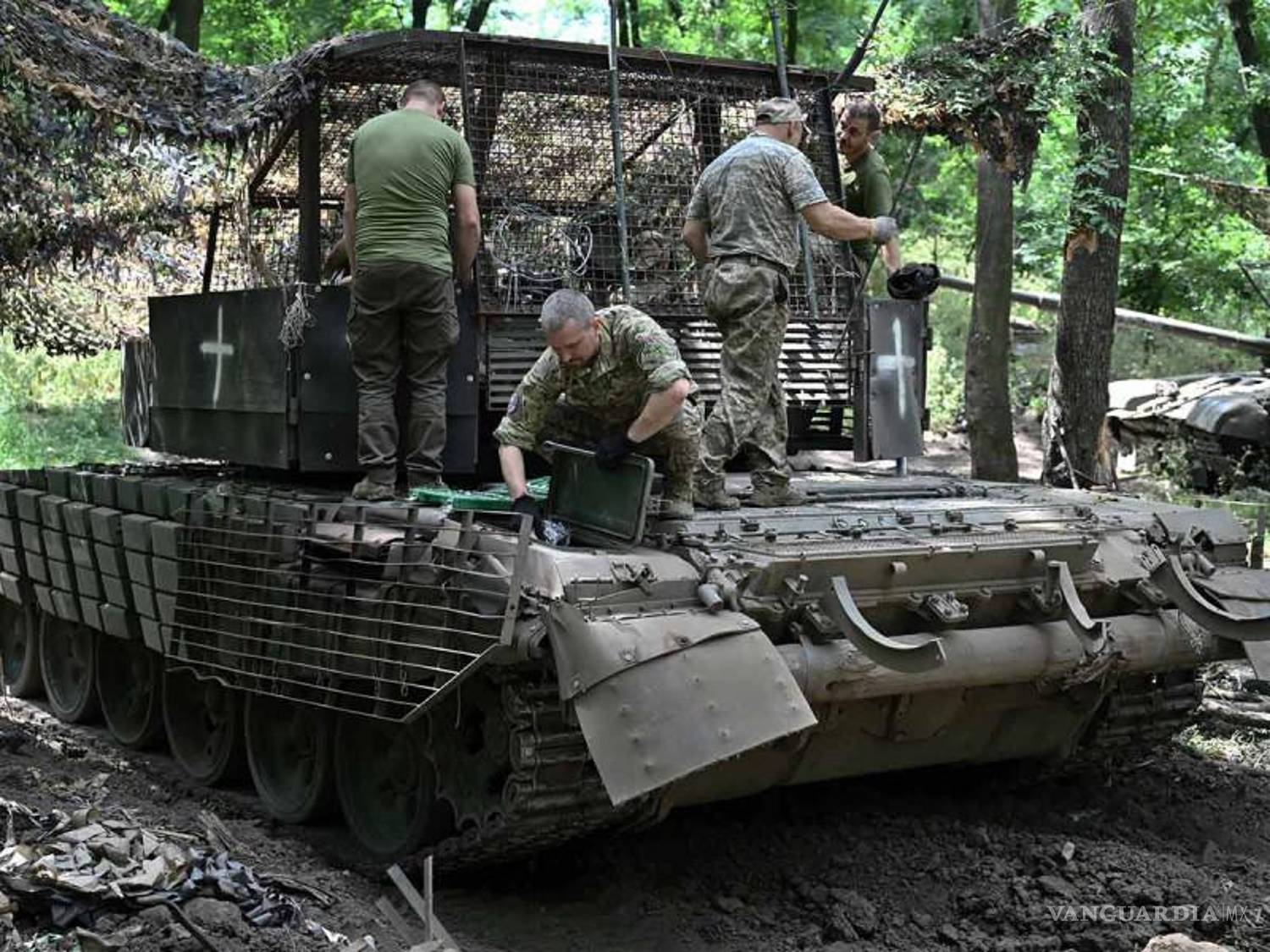 $!Soldados inspeccionan y preparan un tanque modificado en una zona boscosa del frente.
