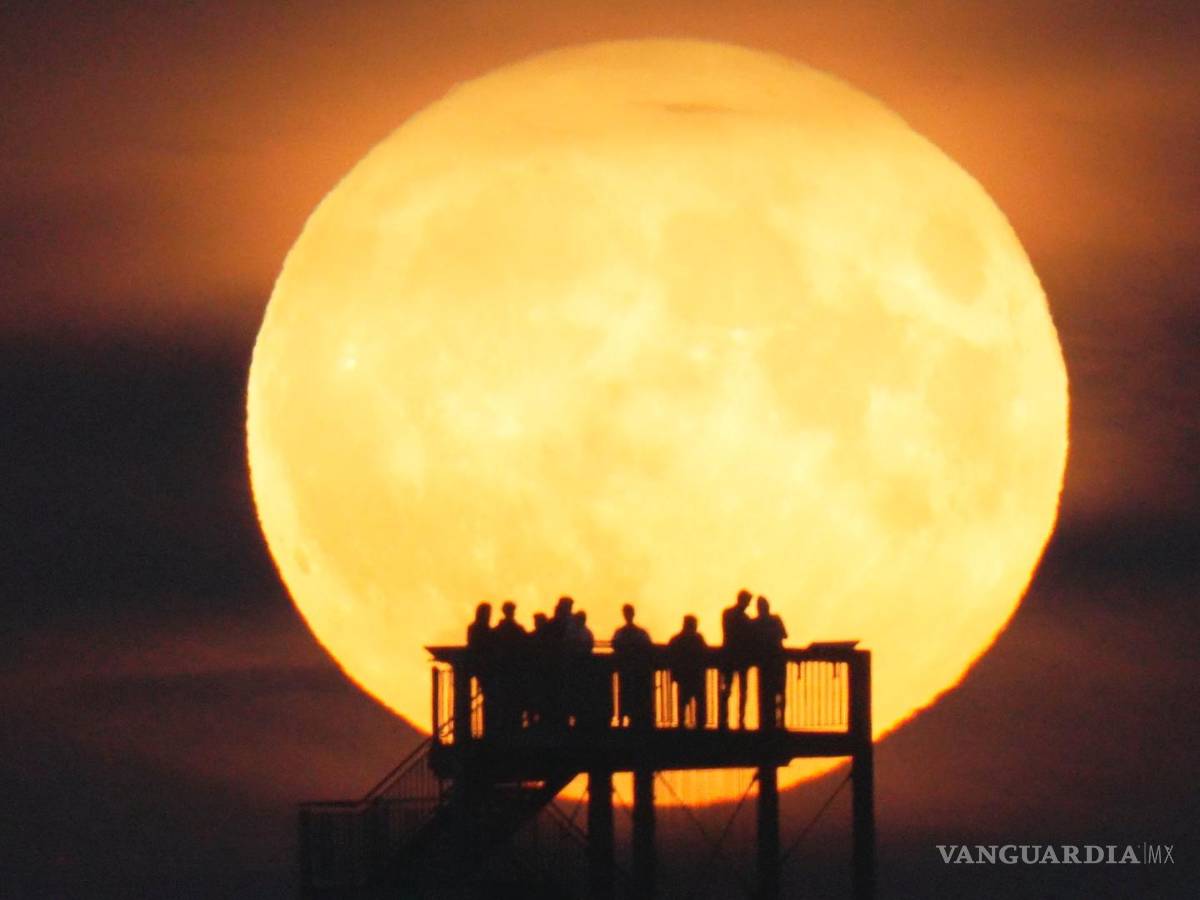 $!La gente ve salir la luna desde la torre de observación en Syke, Alemania, el miércoles 13 de julio de 2022.