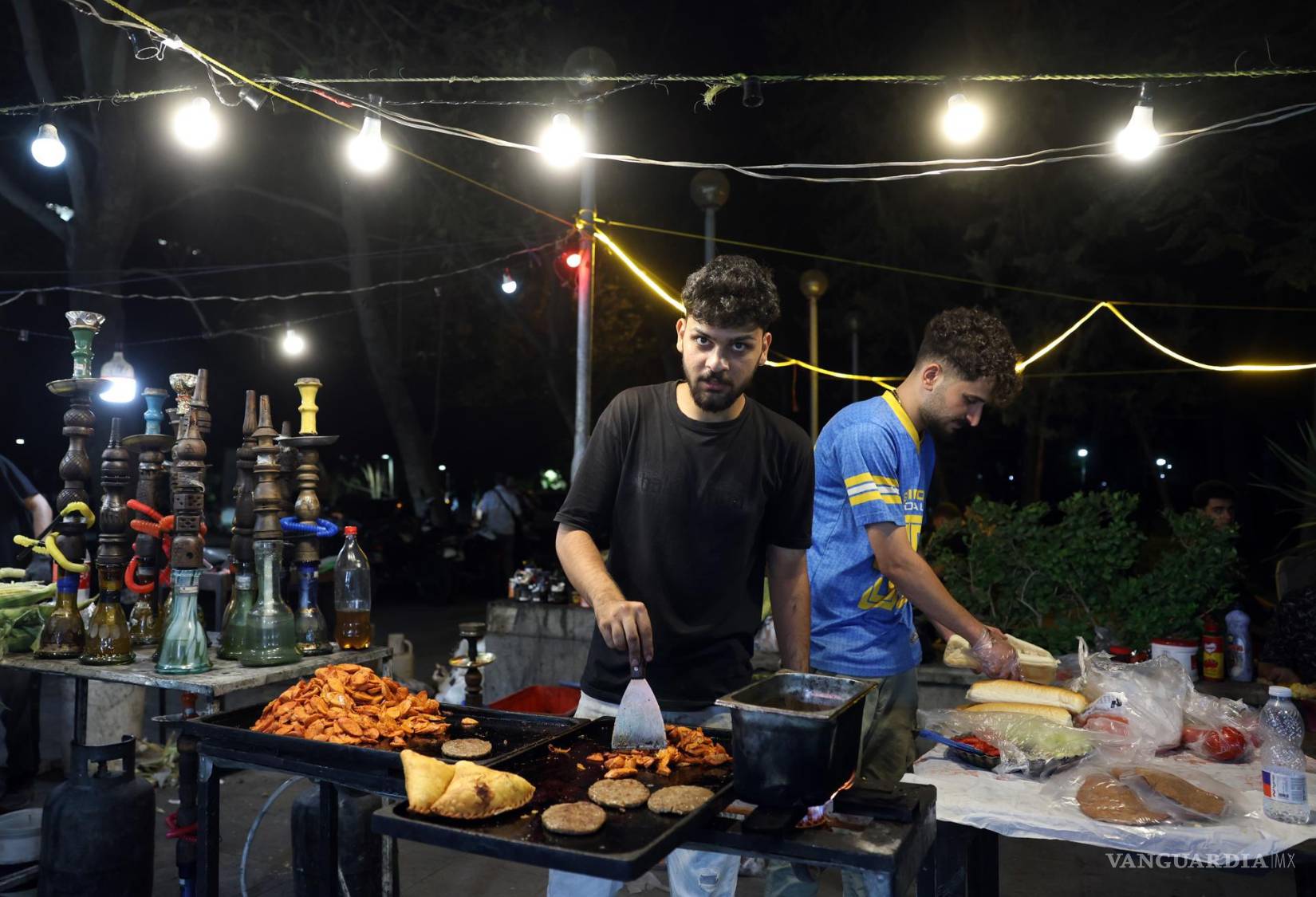 $!Unos iraníes preparan comida callejera en un puesto de mercado en el centro de Teherán, Irán, el 26 de agosto de 2026.