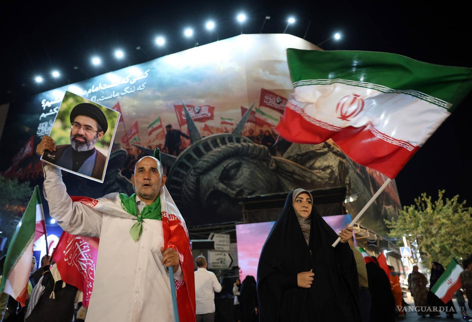 $!Un hombre iraní sostiene un retrato del Líder Supremo, el ayatolá Mojtaba Jamenei, durante una manifestación nocturna contra Estados Unidos en Teherán.