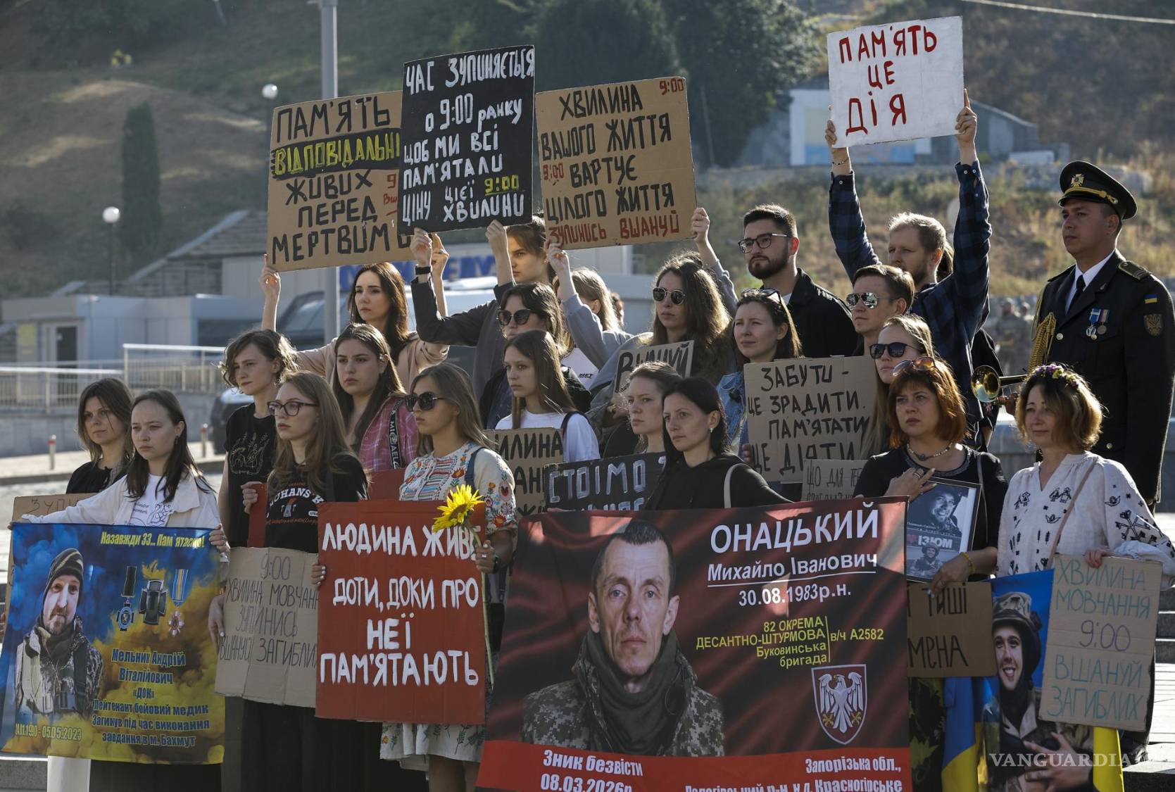 $!Unos ucranianos sostienen pancartas y carteles mientras guardan un minuto de silencio con motivo del Día en Memoria de los Defensores de Ucrania en Kiev.