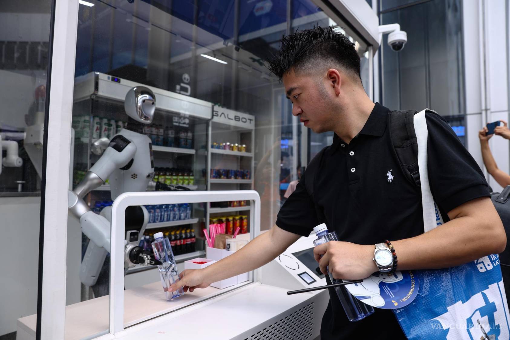 $!Un visitante compra agua embotellada en una tienda automatizada y operada por robots durante la Conferencia Mundial de Robots 2026 en Pekín, China.
