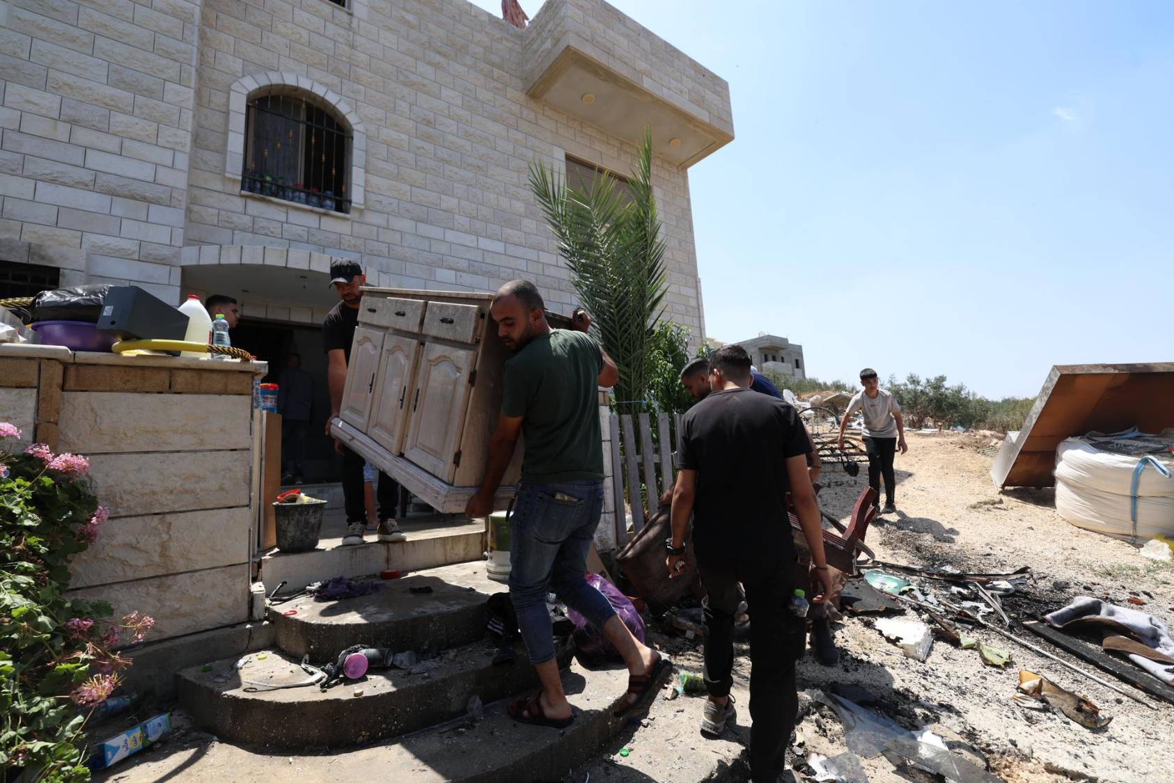 $!Varias personas recuperan objetos calcinados de su casa incendiada tras el ataque de colonos israelíes en la aldea de Sara, en Cisjordania, cerca de Nablus.