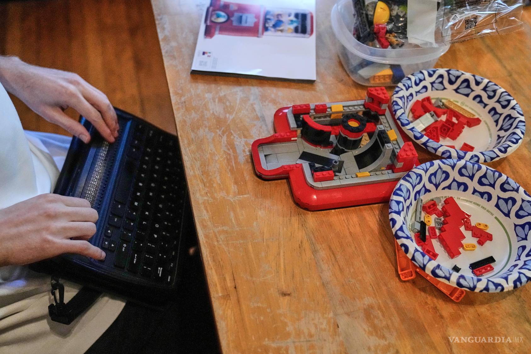 $!Matthew Shifrin, fundador de Bricks for the Blind, lee en una terminal braille mientras construye una máquina expendedora de chicles a base de piezas de Lego.