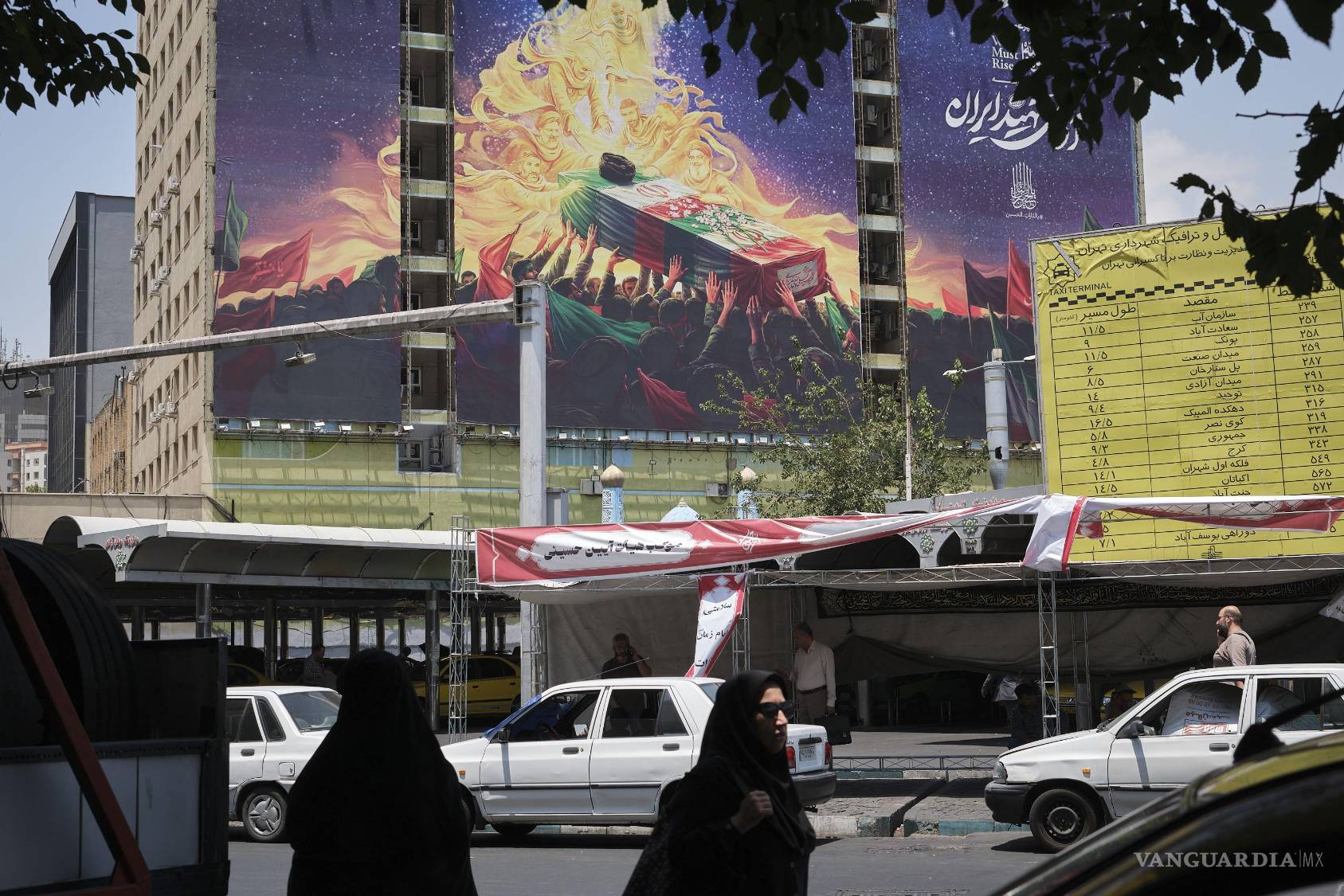 $!Dos mujeres caminan frente a un mural que representa el ataúd del asesinado líder supremo de Irán Alí Jameneí subiendo a los cielos en el norte de Teherán.
