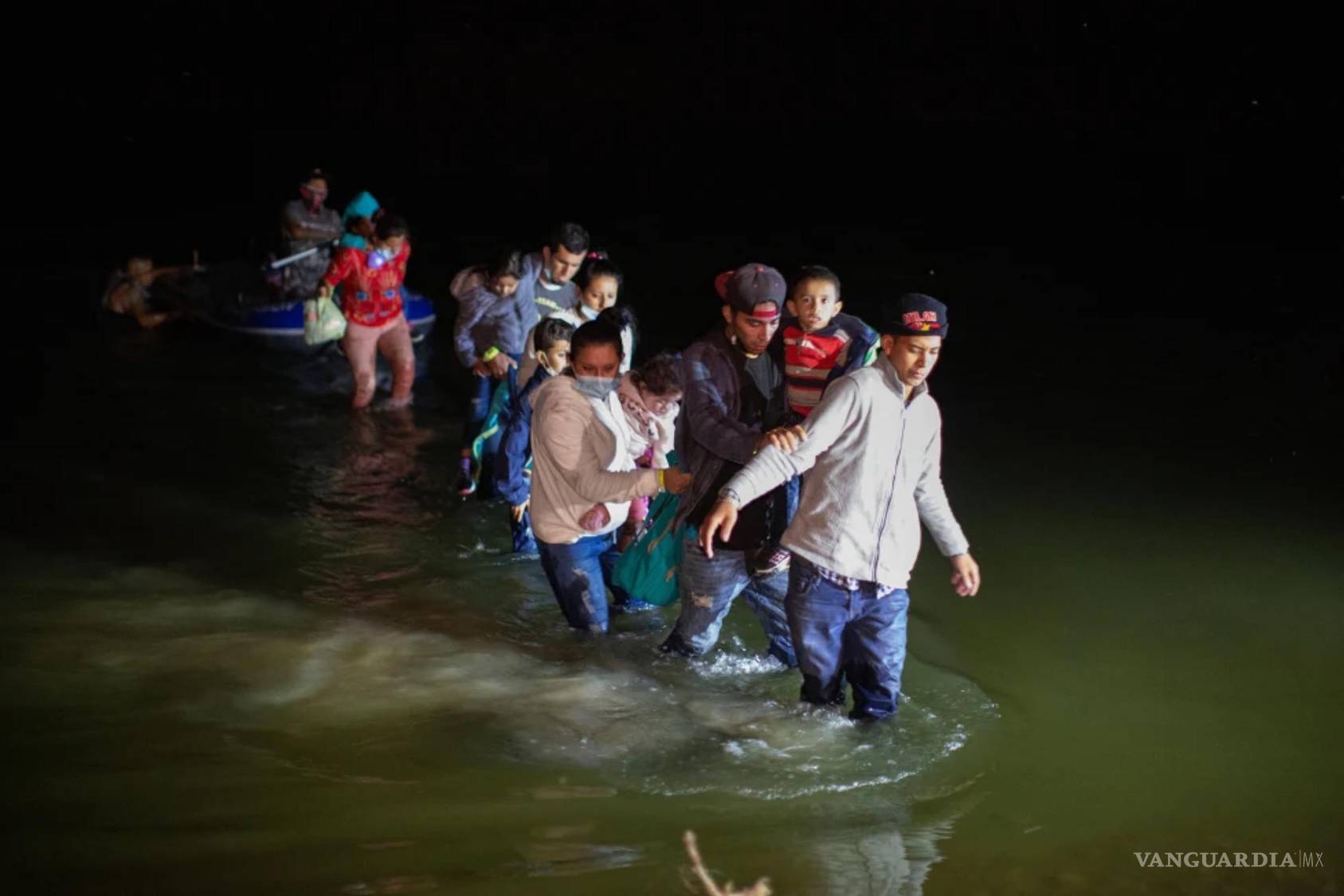 $!Familias migrantes vadean aguas poco profundas en dirección a Roma, Texas, el 24 de marzo de 2021.